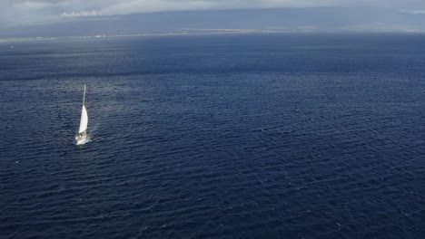 Drone-dolly-view-of-a-white-sailing-boat-sailing-on-the-Auau-Channel-near-Lahaina,-Maui-in-Hawaii