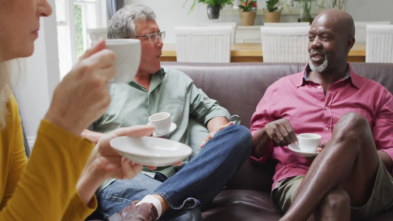 Animation of happy diverse female and male senior friends drinking coffee at home