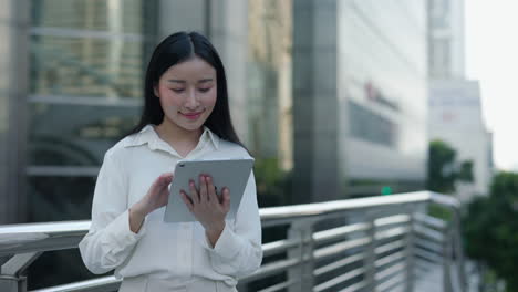 young asian woman using digital tablet outdoors
