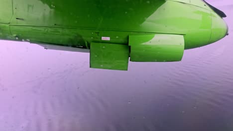wideroe plane lifts off svolvaer runway, passes over sea and retracts gear, seen from window seat