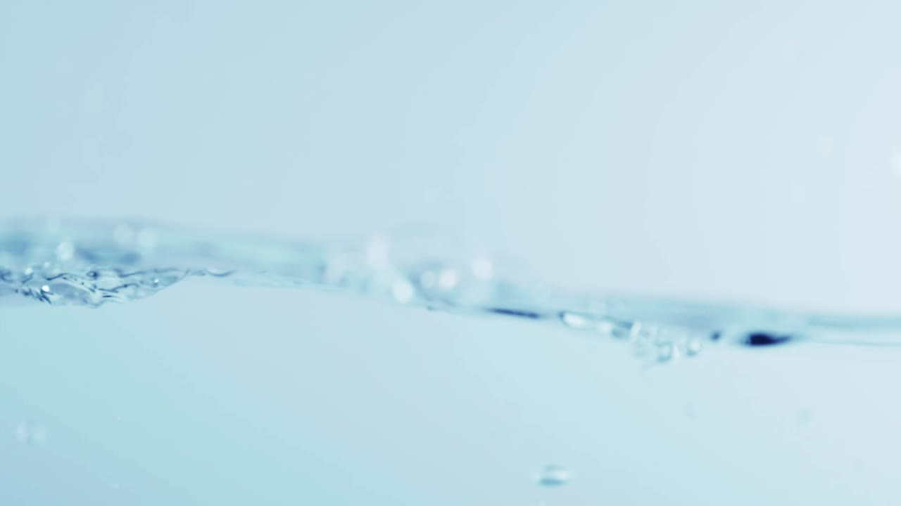 슬로우 모션의 깨끗한 물 표면은 물이 튀는 상점으로 화면을 채우고 기포로 액체 표면을 흔들고 있습니다.