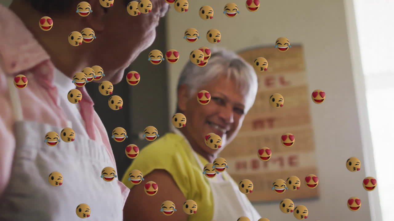 Animation of emoji icons over senior biracial couple cooking in kitchen together