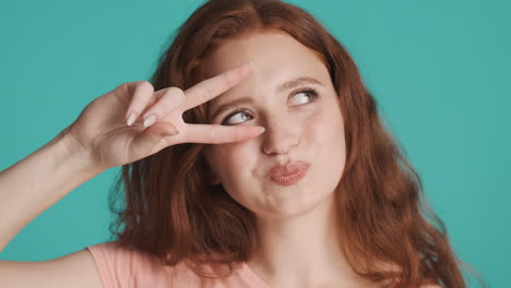 redheaded girl looking at camera on turquoise background.