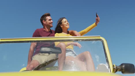 feliz pareja caucásica sentada en un buggy de playa junto al mar hablando