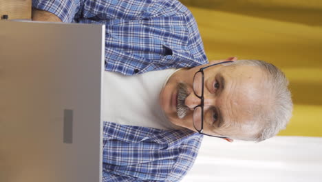 Vertical video of Old man looking at laptop in amazement.