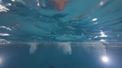 Underwater-diving-view-of-a-swimmer-going-out-up-of-the-pool-shaking-water-and-showers,-water-sports