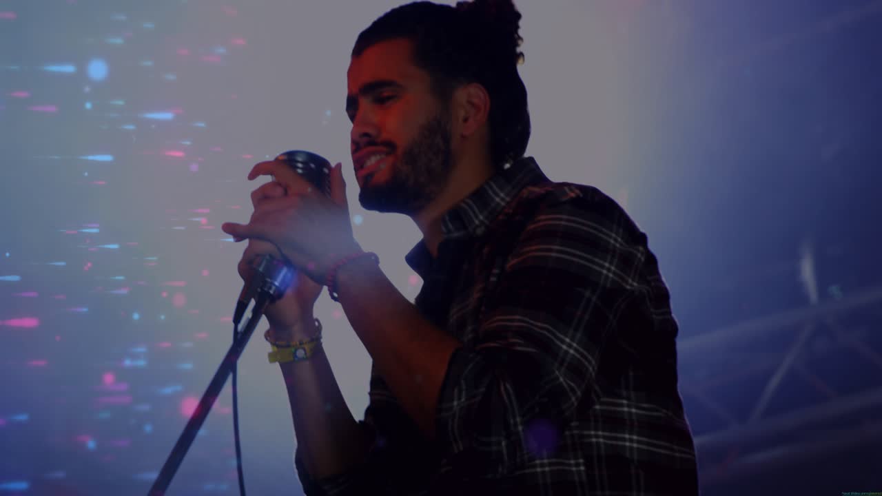 Male singer gripping vintage mic and performing song on music stage backlight flaring into shadow