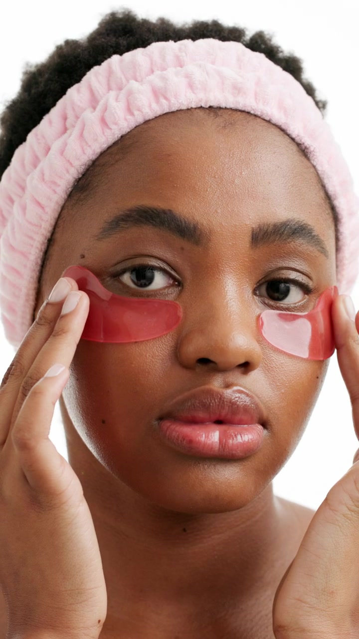Young Woman Applying Red Under-Eye Patches for Skincare Routine