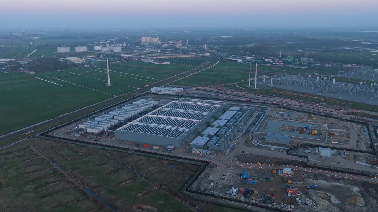 Vast aerial perspective of a modern hyperscale data center during construction, featuring rooftops covered with solar panels for renewable energy