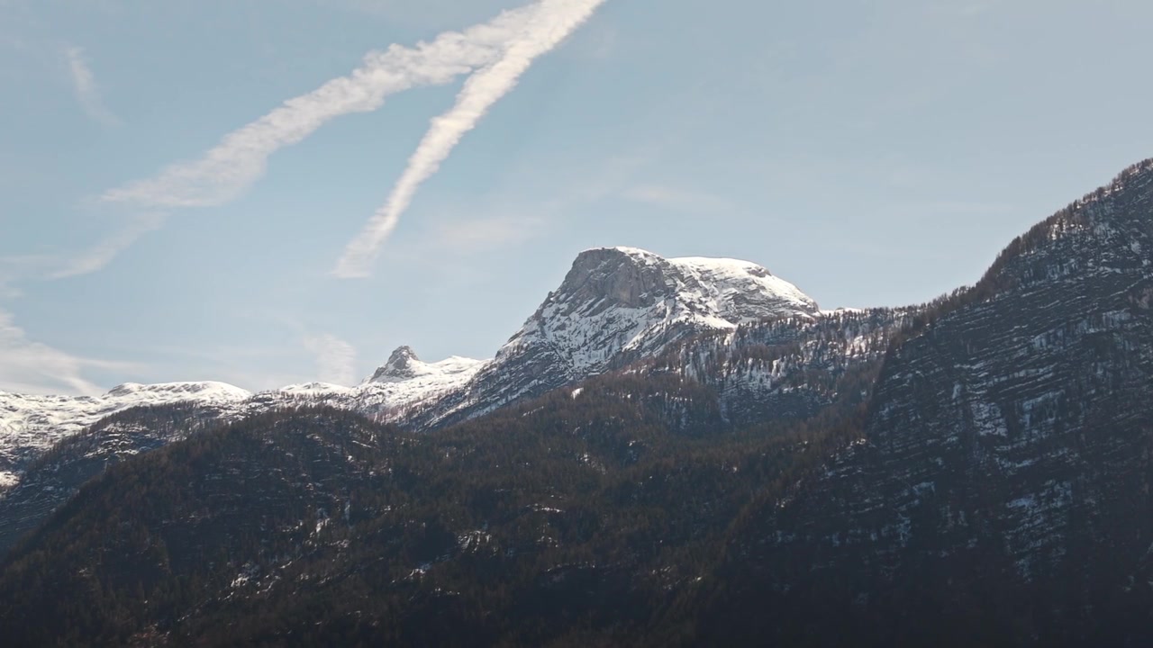 Laaja vuoristomaisema Banff National Parkissa, Albertassa, Kanadassa, jossa lumipeitteinen Mount Rundle kohoaa sinisen taivaan ja hahtuvapilvien alla karujen huippujen yllä.