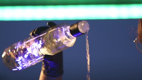 a person pours a bottle of liquor into a glass