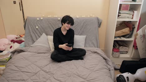 A-teen-girl-browsing-her-smartphone-at-home,-on-her-bed-