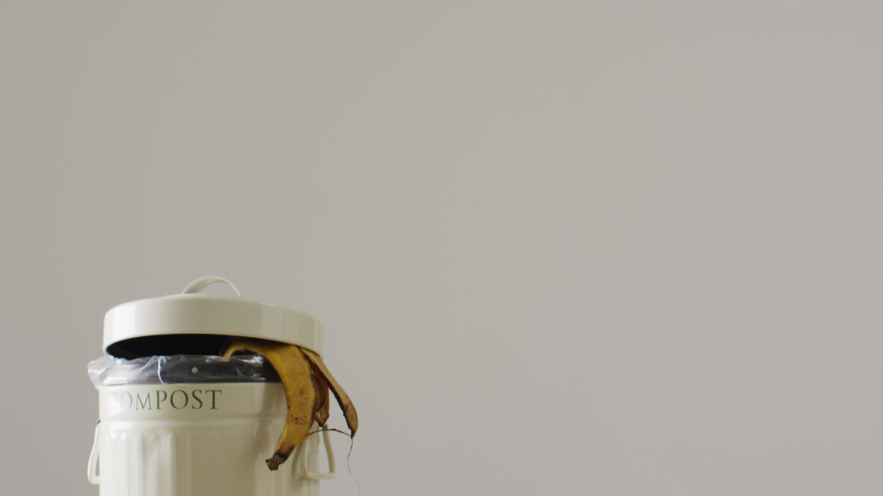 바나나와 바나나 피부  ⁇ 어리의 비디오가 완전한 주방 컴포스팅 빈에서 매달려 있습니다.
