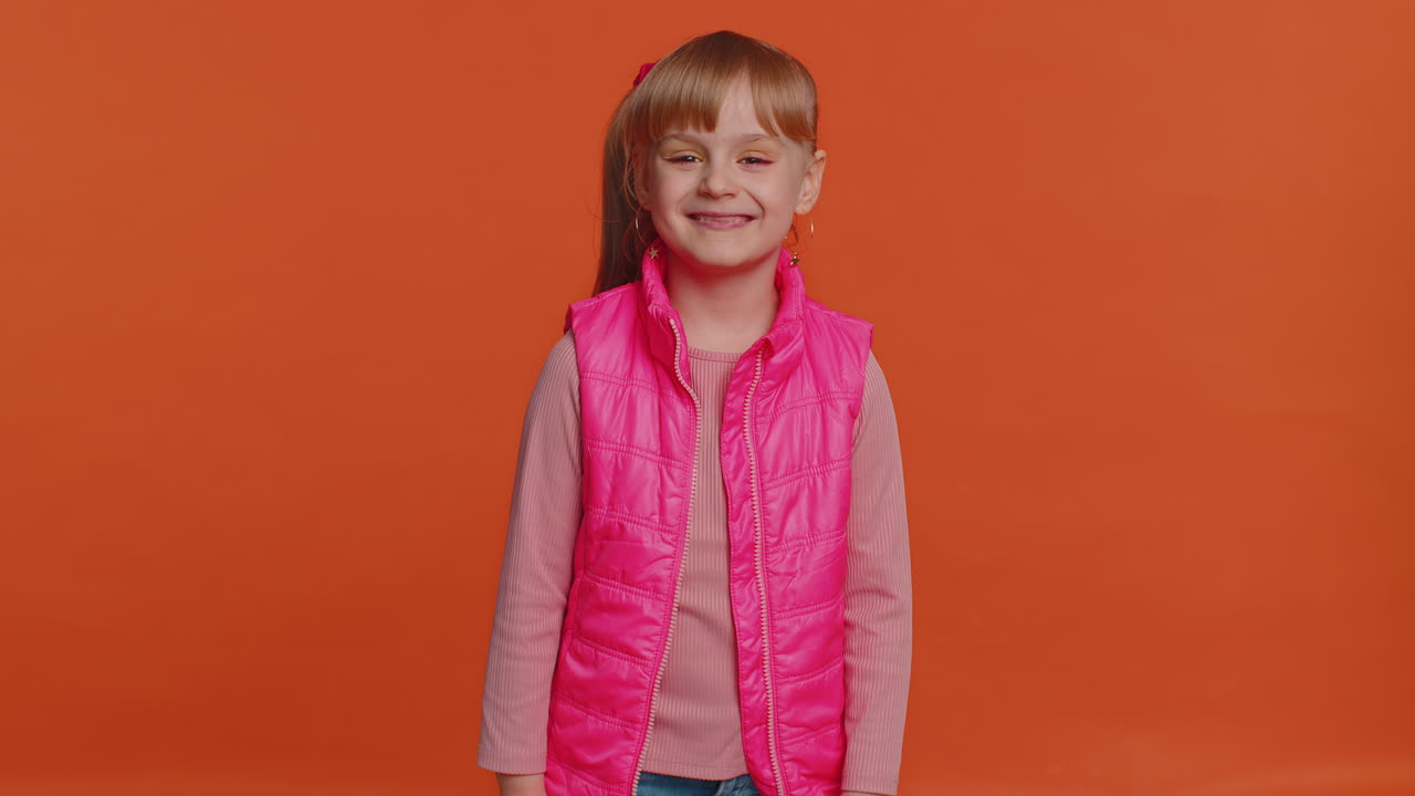 encantadora chica alegre niño aprueba la sugerencia, sacudiendo la cabeza con aprobación, satisfecho con el buen trabajo, como