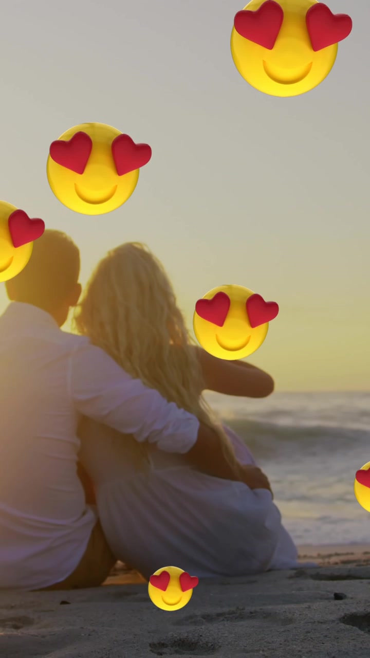 Sahilde birbirine sarılan çiftin önünde süzülen çok sayıda kalp gözlü yüz emojisi.