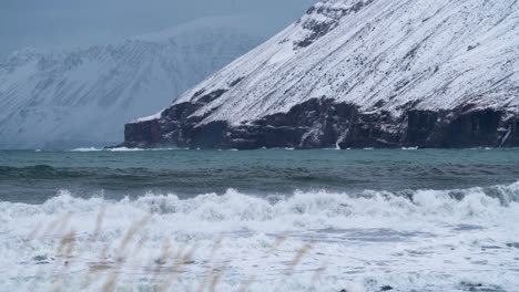 low angle shot of arctic ocean waves hit the coast of ólafsfjörður town during cold freezing and snowy icy conditions in november