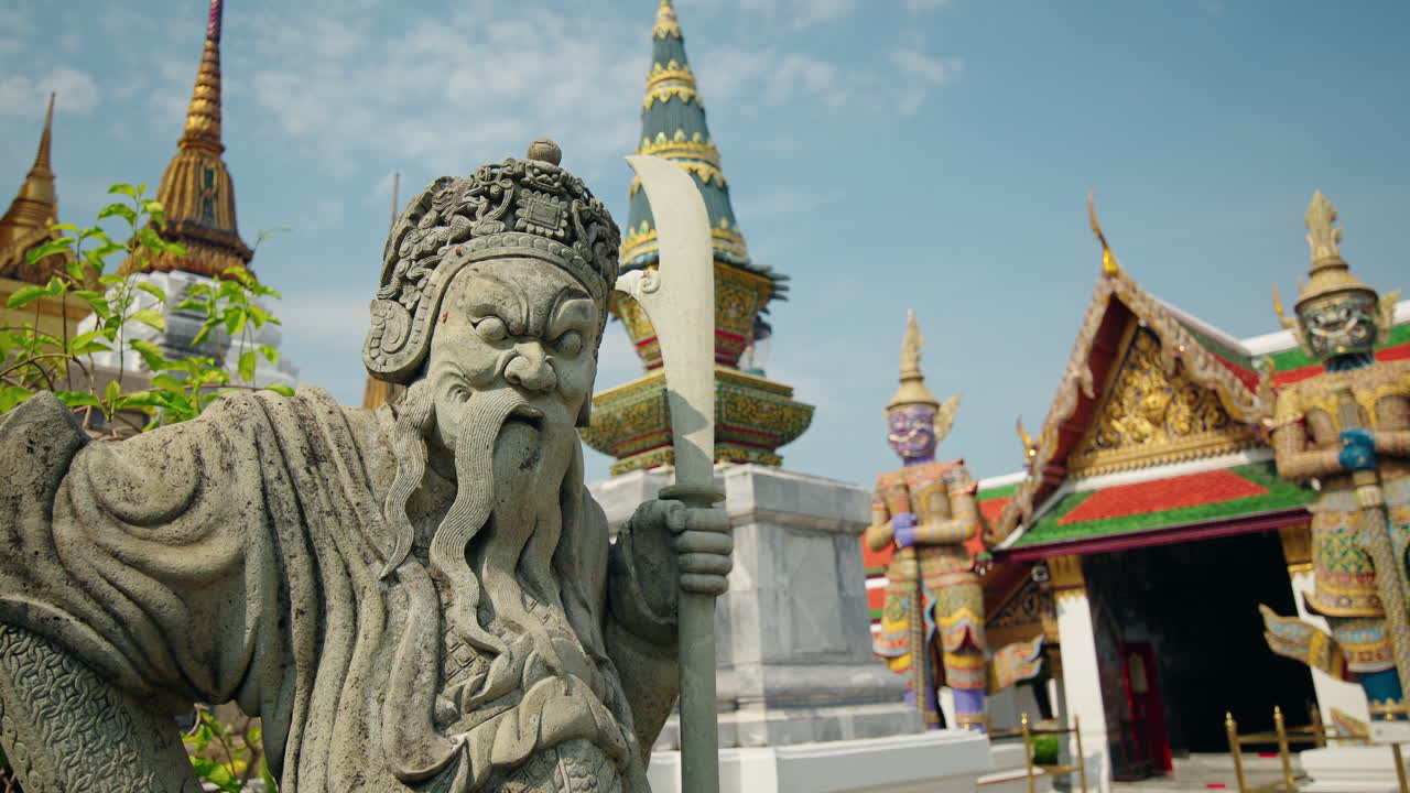 Bangkok'taki Wat Phra Kaew'de kılıç tutan antik taş koruyucu, ikonik Tay tapınak kompleksi ve kültürel simge yapı