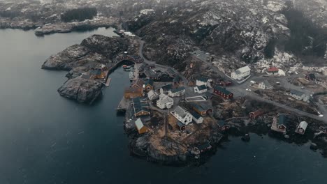 snow falling in nusfjord village, mountain and vestfjorden in winter in flakstadoya, norway. - aerial shot