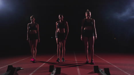 corredoras en la pista de atletismo agachadas en los bloques de salida antes de una carrera. en cámara lenta.