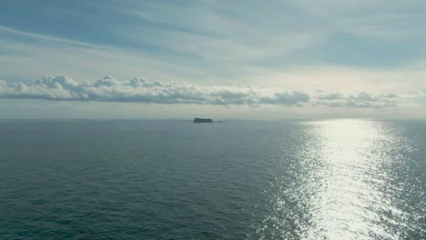 slow aerial flight towards the island of filfla off the coast of malta in the mediterranean ocean following the glistening setting sun