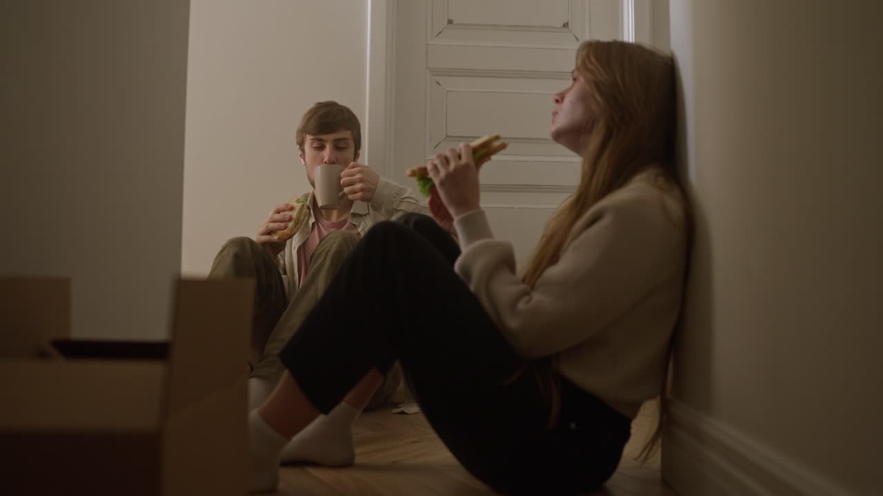 пара ест сэндвичи и кофе во время переезда.