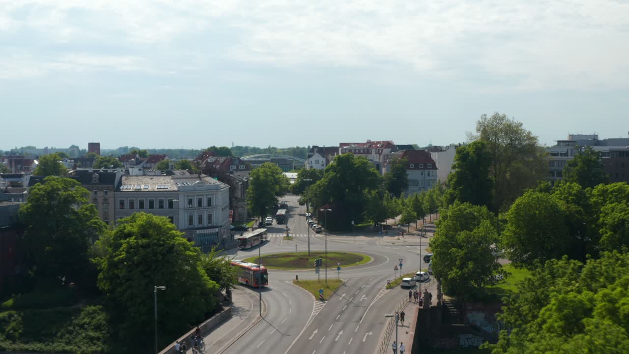 Forwards reveal of roundabout. Aerial view of main road with low traffic leading through town. Luebeck, Schleswig-Holstein, Germany