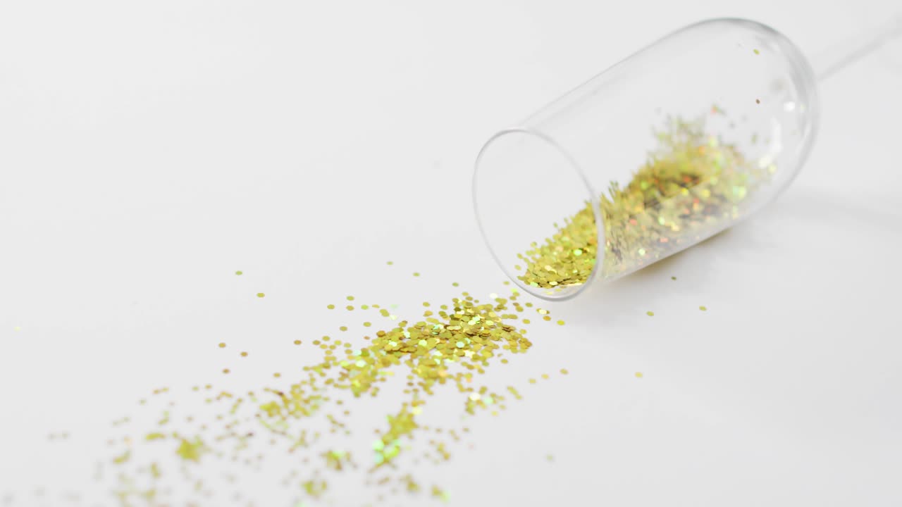 Tipped glass spilling glitter while text appearing causing tree and stars forming MERRY XMAS