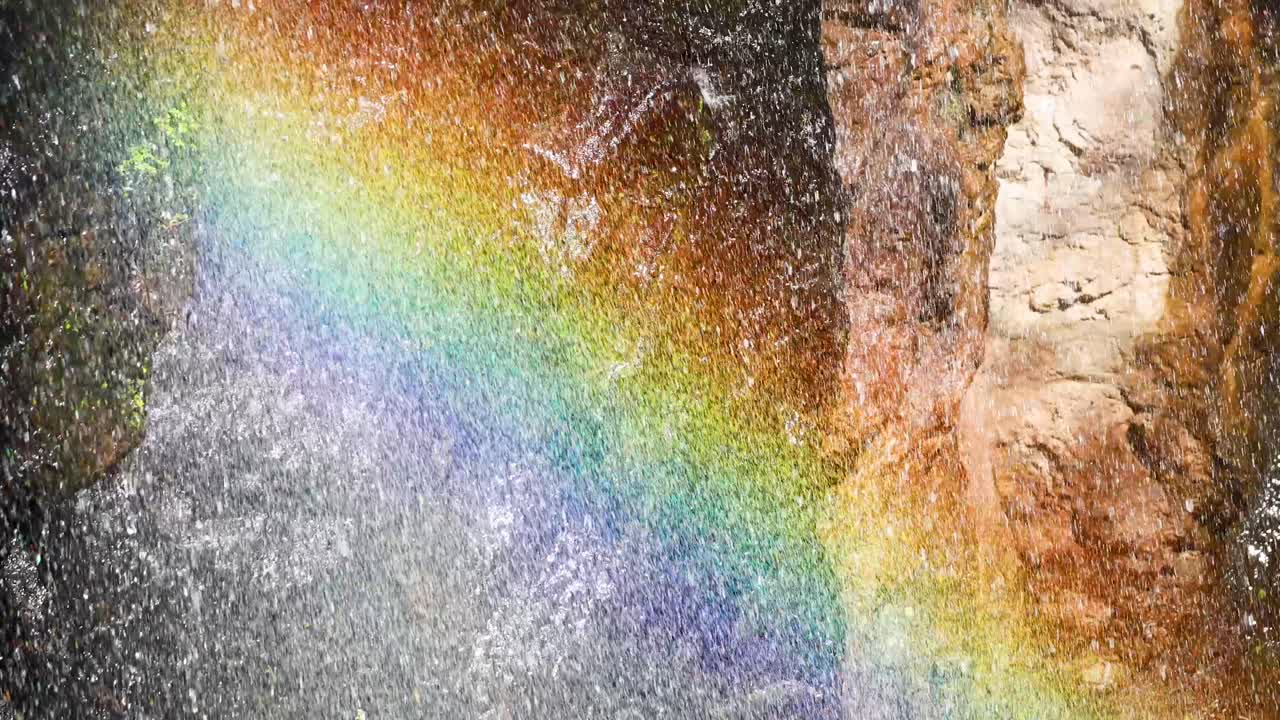 Vibrant rainbow arches over cascading waterfall