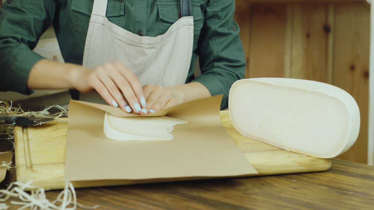 retrato del amable vendedor desempaqueta el trozo de queso y luego sonríe a la cámara