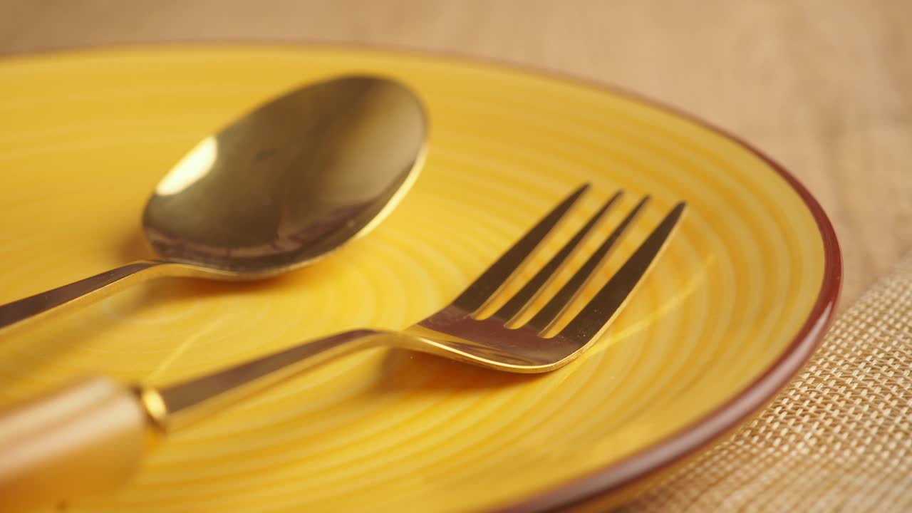 Close-up of Golden Cutlery on Yellow Plate