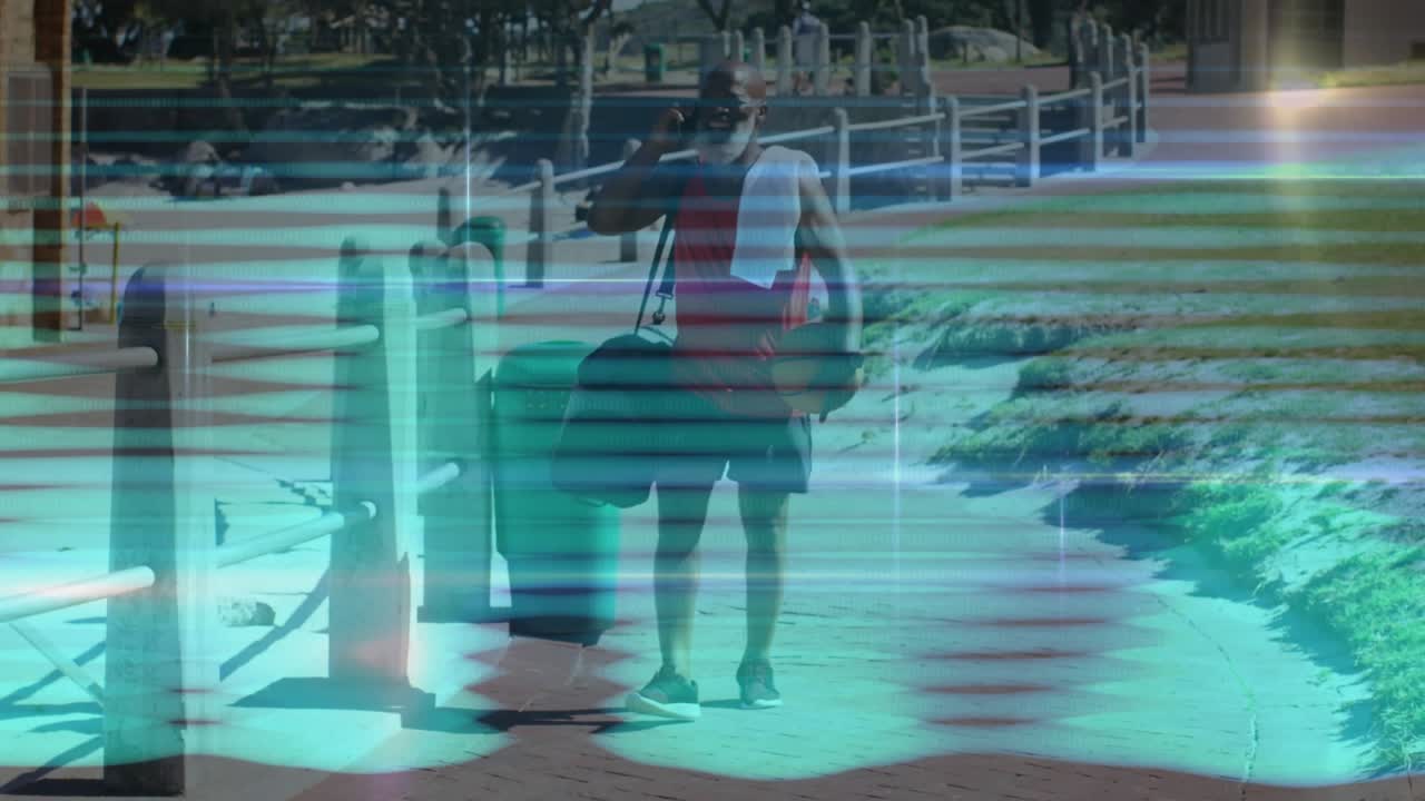 Man entering waterfront path while talking on phone and carrying basketball bag for sports practice