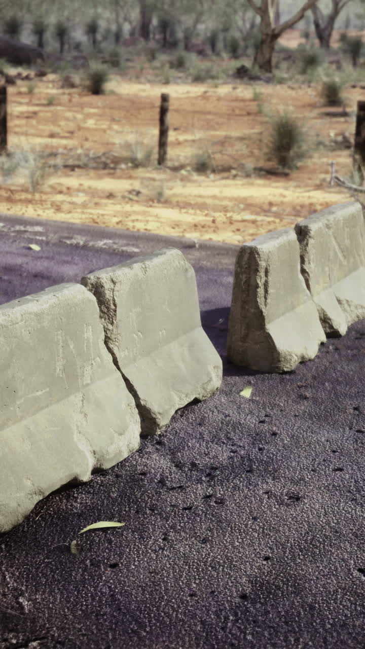 Road barriers disrupt travel in a remote desert landscape under the sun