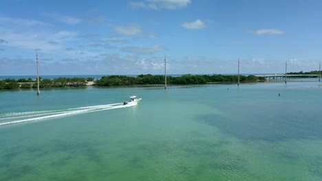 Drone-Shot-of-boat-cruising-along-US-1-approaching-Robbie's-Marina-in-Islamorada,-Florida-Keys