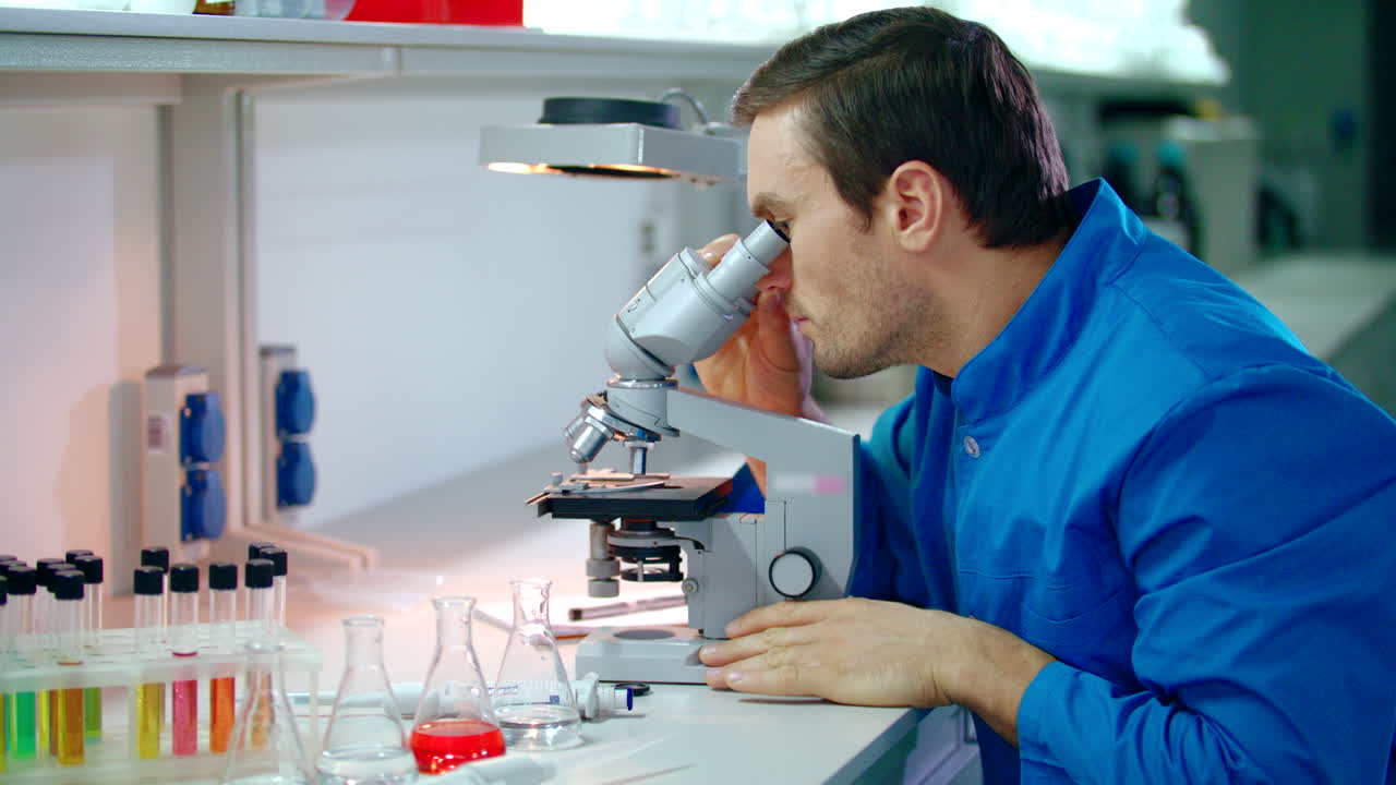científico masculino haciendo investigación con el microscopio. científico hombre mirando al microscopio