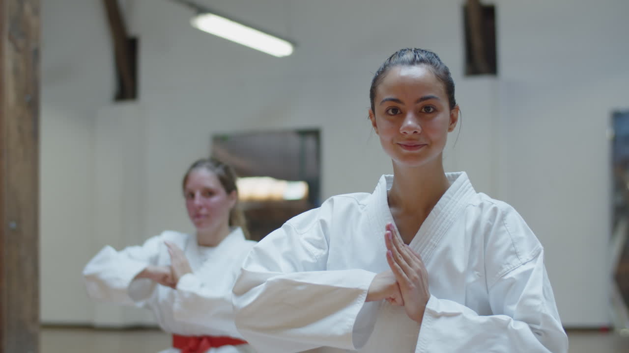 vista frontal de linda chica en kimono mostrando gesto de palma y puño
