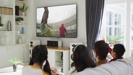 Composite-of-happy-family-sitting-at-home-together-watching-rugby-match-on-tv