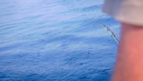 hombre en barco en medio del mar con cordón de pesca para buscar peces