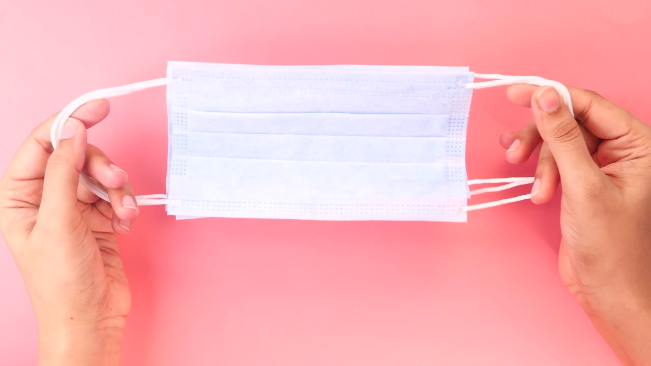 manos sosteniendo una máscara facial azul claro