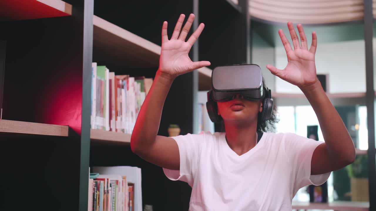 A schoolgirl sitting in front of library's bookshelf and using virtual reality glasses.