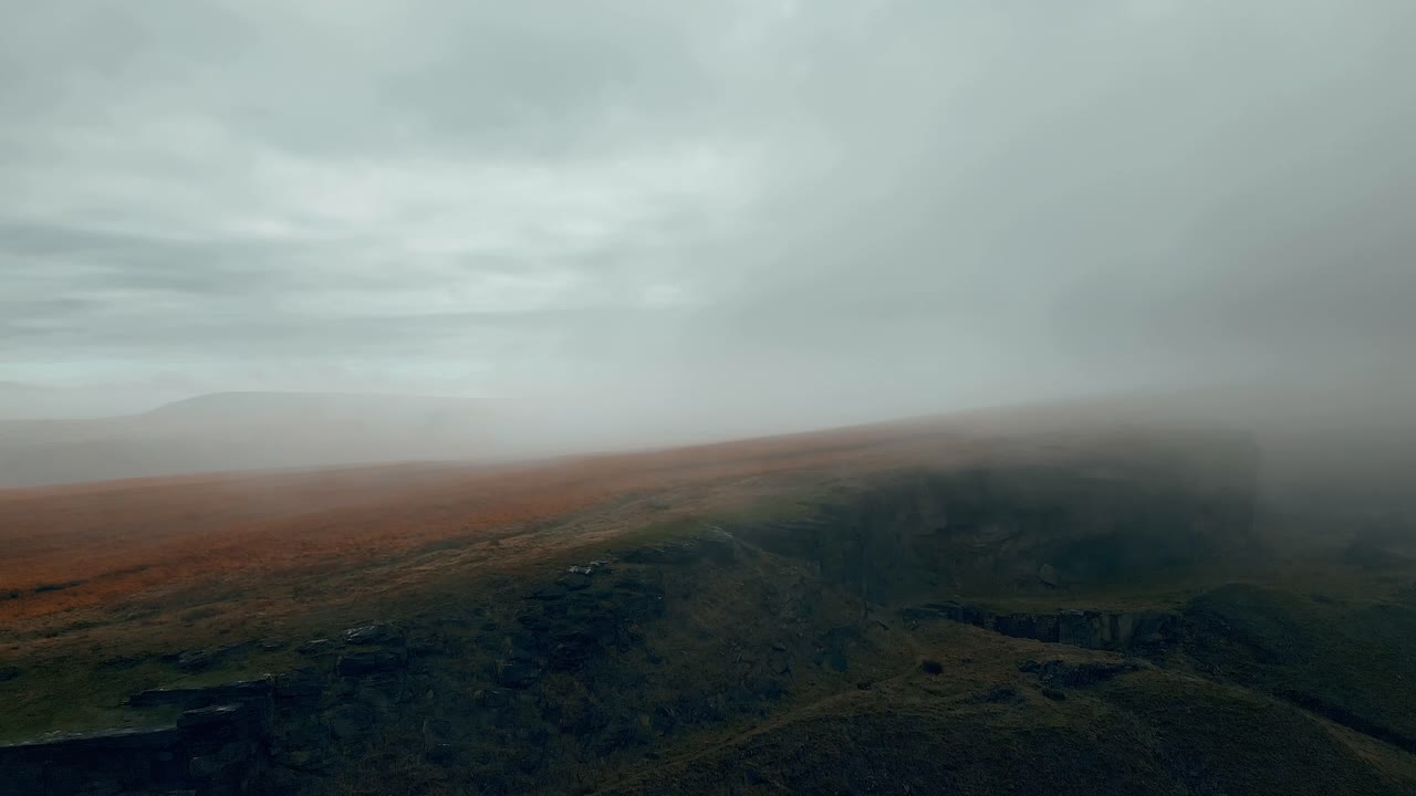 Aerial drone view of morning mists moving slowly over the damp rugged Pennine hills, on a foggy morning, golden hills and beautiful rocky cliffs and moorlands