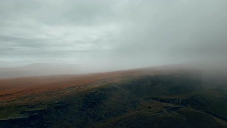vista aérea por drones de las nieblas matutinas moviéndose lentamente sobre las colinas peninas escarpadas y húmedas, en una mañana nublada, colinas doradas y hermosos acantilados rocosos y páramos