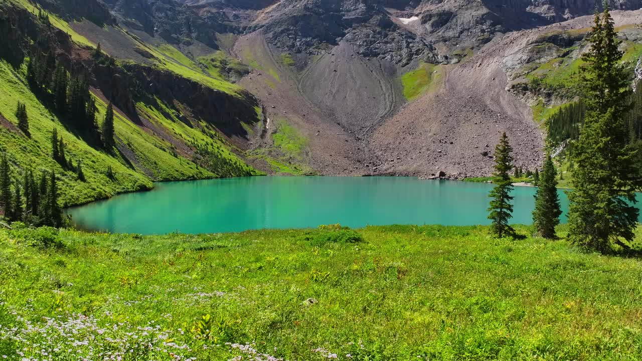 Lower Blue Lake Mount Sneffels Wilderness beautiful sunny morning Ridgway Telluride Colorado aerial drone forward pan motion San Juan Rocky Mountains Dallas Range wildflowers blue sky hiking trails