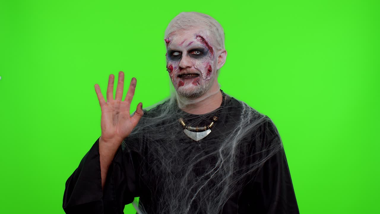 Inquietante uomo zombie di Halloween che sorride amichevolmente, agita le mani per salutare o dire addio, dando il benvenuto.