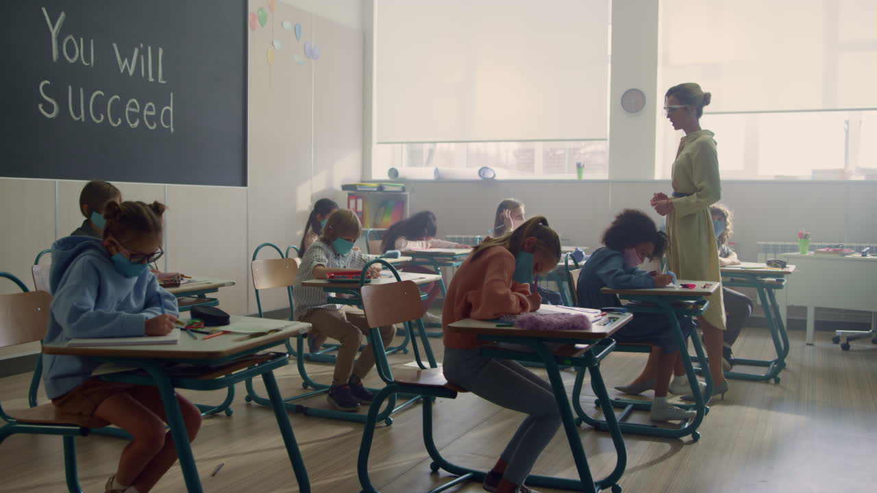 Kids in medical masks studying together in classroom during coronavirus pandemic