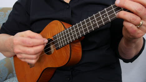 close up view of woman playing a ukulele, no face, plucking strings, handheld