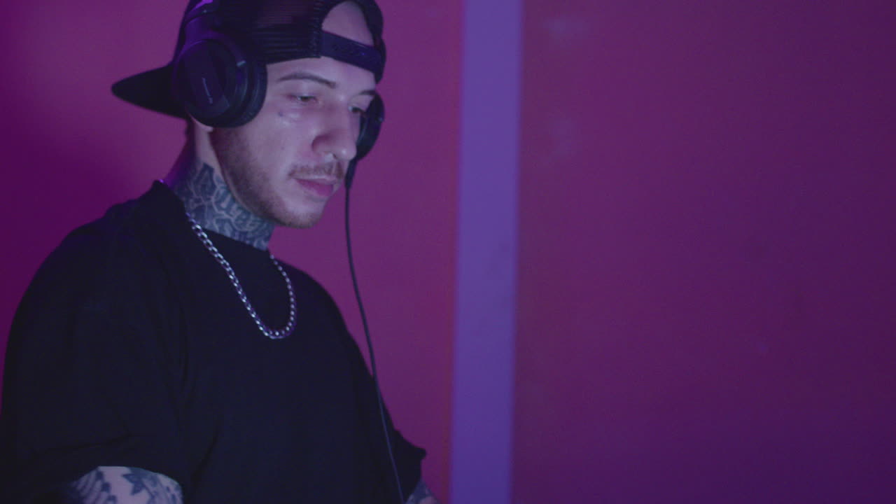 A DJ performs in a lively club with vibrant lights and an energetic crowd at night