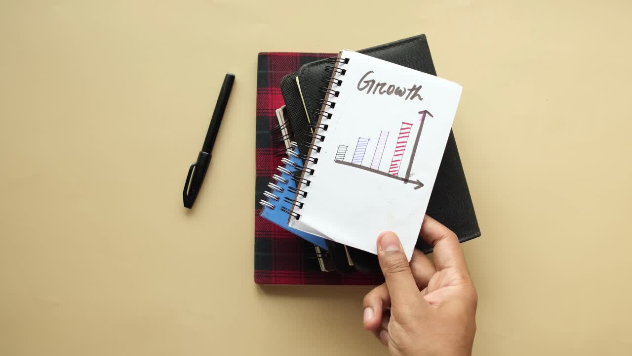 Hand holding notebook with growth chart drawing
