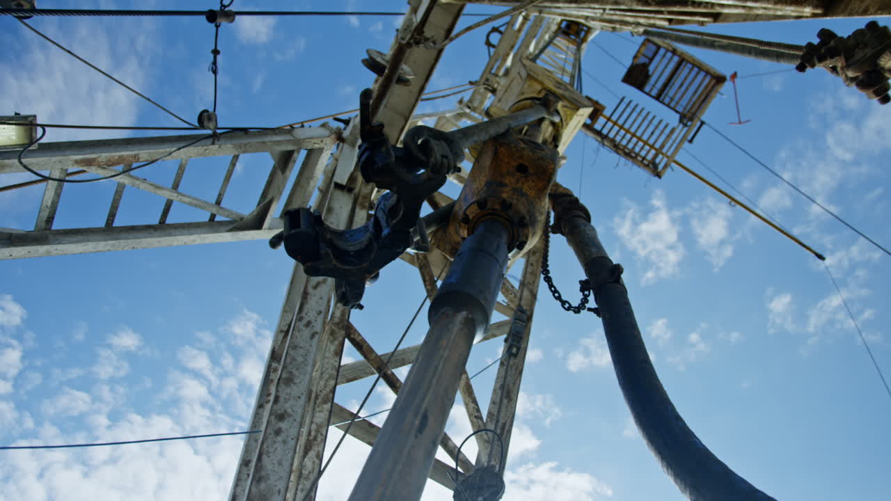 Metal pole rotating while drilling the oil or gas. Low angle view on the equipment for gas and oil production.