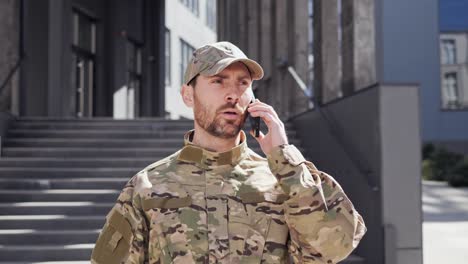 army soldier having online mobile phone call with his superiors outdoors.