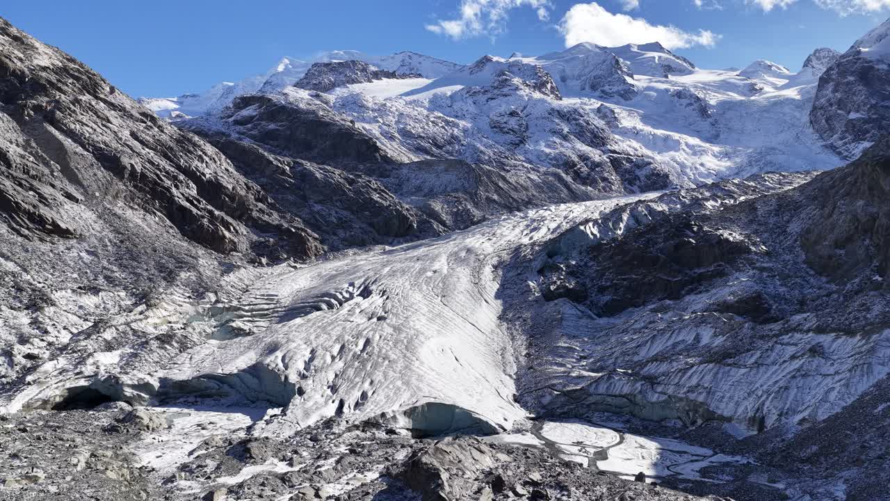 Engadin glacier in Switzerland with snow mountains and blue sky, drone pullback over stunning alpine landscape from Sankt Moritz region, natural beauty of Swiss alps